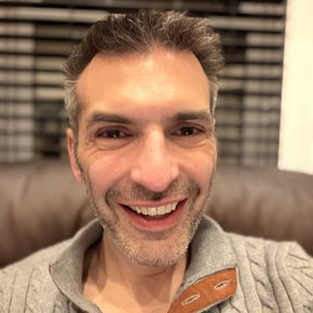 Lex Friedman, smiling, in a grey cable-knit sweater.